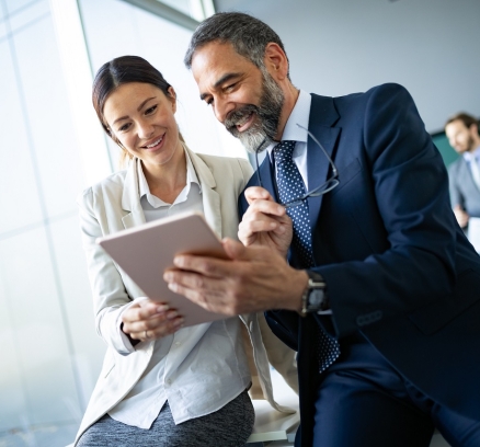 Happy business colleagues in modern office talking and using tablet