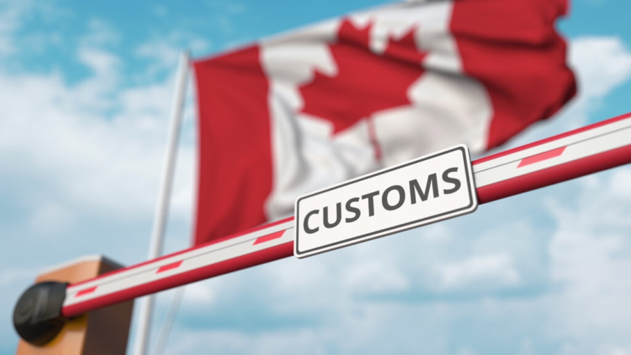 Closing,Boom,Barrier,With,Customs,Sign,Against,The,Canadian,Flag.